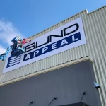 Man securing Blind Appeal banner to building